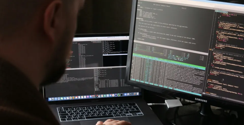 An engineer working with terminal windows and system monitoring across two screens.