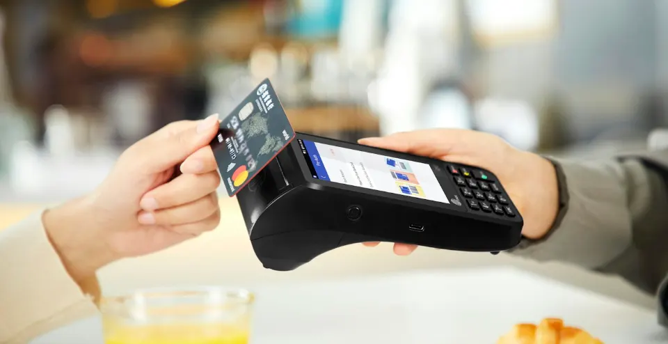 A customer making a contactless card payment at a handheld payment terminal.
